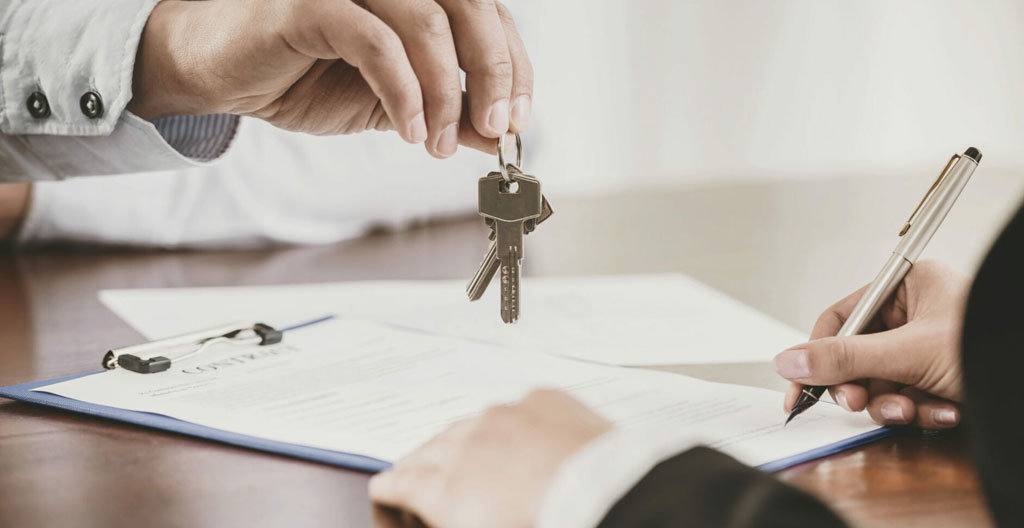 Mains d'un propriétaire et d'un conseiller immobilier au-dessus d'un contrat de mandat de gestion locative prêt à être signé